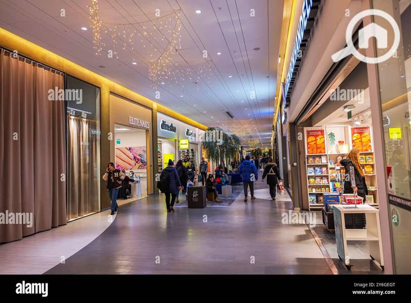 9 shoppers-walking-through-a-brightly-lit-shopping-mall-with-boutiques-and-christmas-decorations-hanging-above-2Y6GEGT. jpg