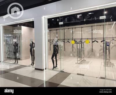 محلات تجارية  للبيع في العاصمة الإدارية الجديدة، القاهرة - the-window-of-an-empty-clothing-store-with-black-mannequins-and-empty-hangers-2M73AFB. jpg