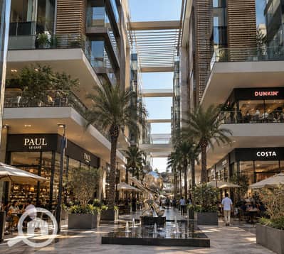 محلات تجارية  للبيع في 6 اكتوبر، الجيزة - Upscale Open-Air Mall Promenade with Chrome Sculpture. png